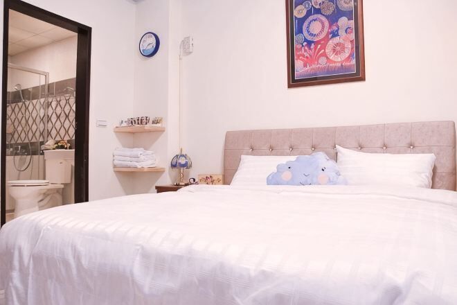 Un dormitorio con una cama, una mesita de noche, una lámpara, un reloj de pared y un cuadro enmarcado.