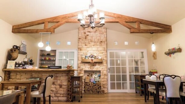A spacious dining area with a stone fireplace, wooden beams, and a chandelier. - Booksnwoods (Taitung)