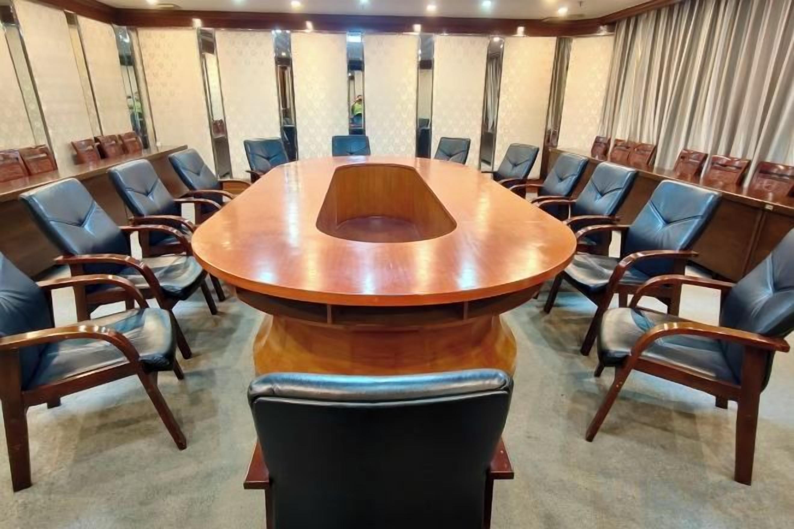 A conference room with a round table, multiple chairs, and a carpeted floor.
