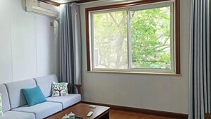 Una sala de estar con un sofá, una mesa de centro y un amplio ventanal con cortinas.