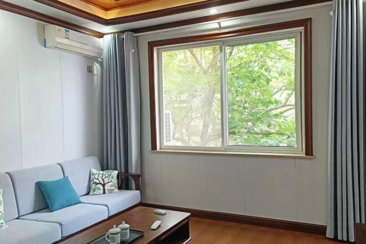 Una sala de estar con un sofá, una mesa de centro y un amplio ventanal con cortinas.