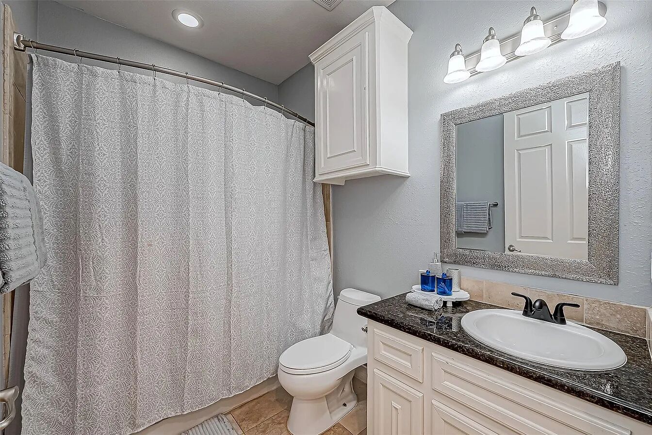 Une salle de bain équipée d’un rideau de douche, de toilettes, d’un lavabo et d’un miroir.