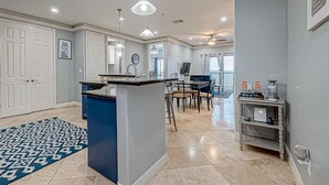 Une cuisine spacieuse dotée d’un îlot central, de luminaires suspendus et d’un coin repas avec des chaises et une table.