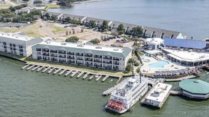 Un grand hôtel à plusieurs étages, doté d’une piscine et d’un quai avec un bateau.