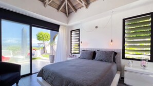 Ein modernes Schlafzimmer mit einem großen Bett, einer Schiebetür zum Balkon und einer eingebauten Bepflanzung mit Grünpflanzen.