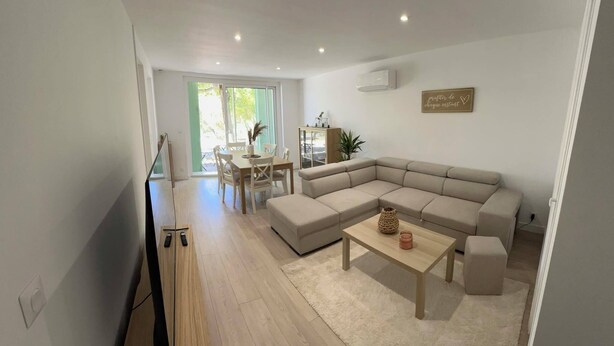 A modern living room with a sectional sofa, a coffee table, and a dining area with chairs and a table.