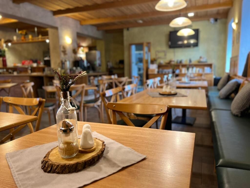 Een gezellig restaurantinterieur met houten tafels en stoelen, een houten plafond en een aan de muur bevestigde televisie.