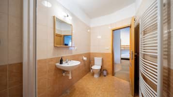 Et moderne badeværelse med vask, toilet og bruser.