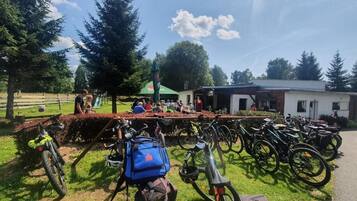 A row of bicycles parked in a grassy area with a building in the background.