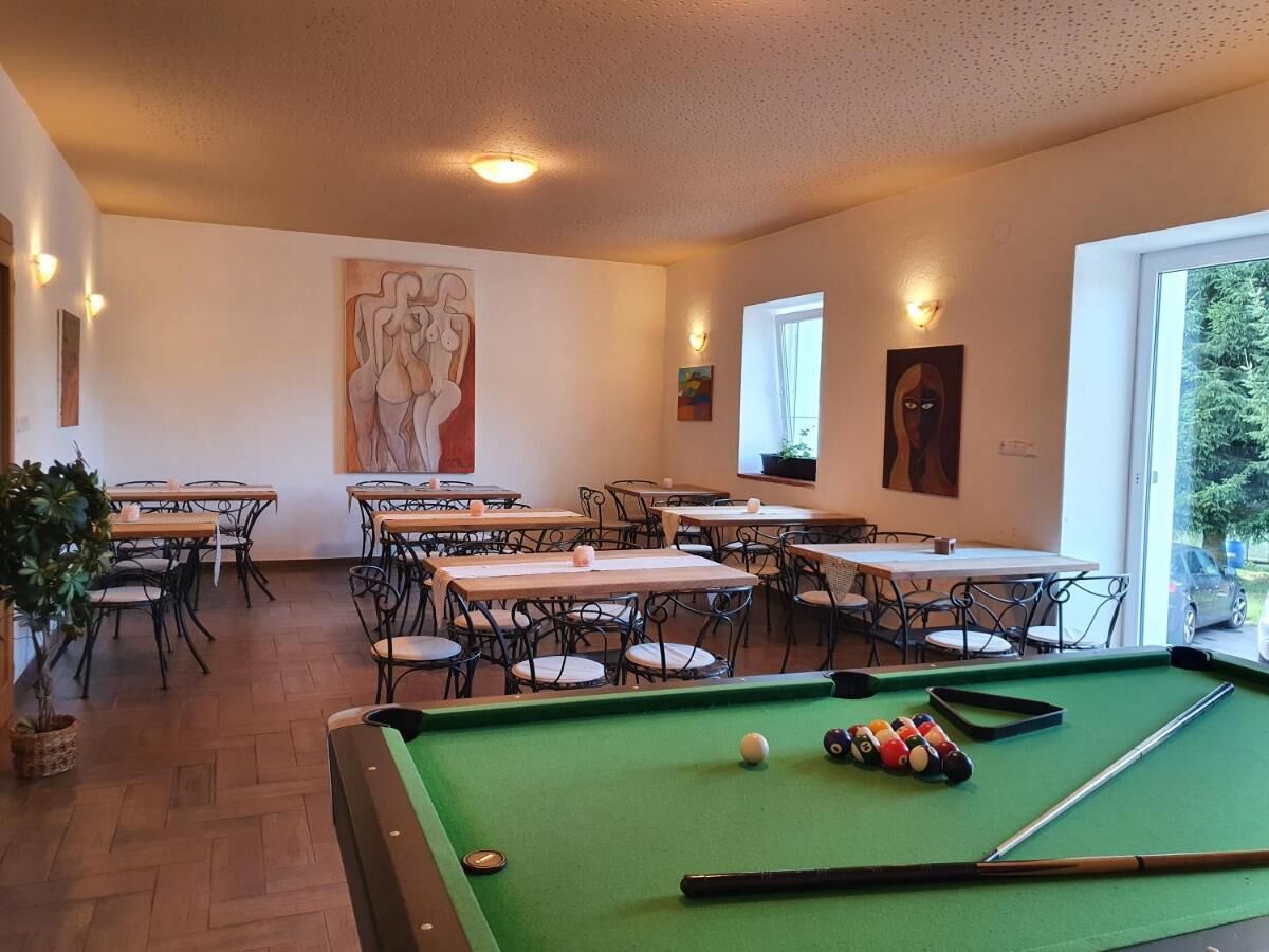 A billiards room with tables and chairs, a pool table, and artwork on the walls.