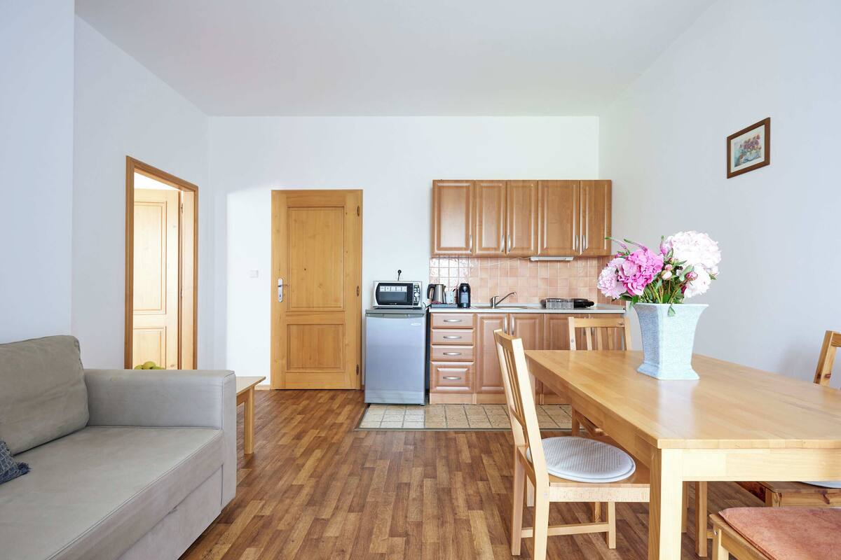 A compact kitchen with wooden cabinets, a refrigerator, and a dining table with chairs.