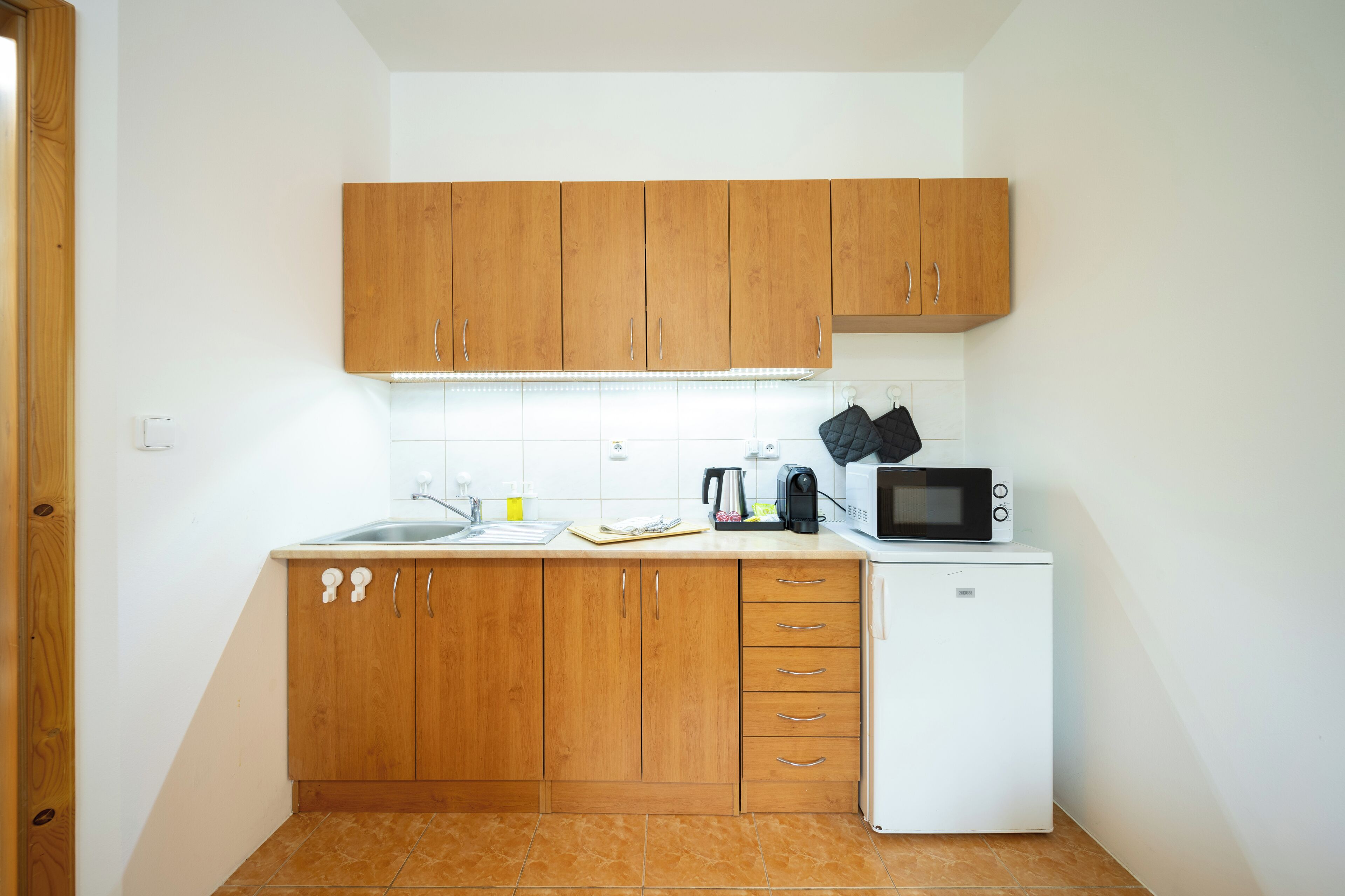 A small kitchen with wooden cabinets, a white refrigerator, and a microwave.