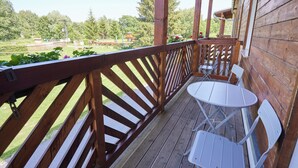 A wooden deck with a table and chairs, overlooking a garden and trees. - Resort Pasečná (Prední Výton)