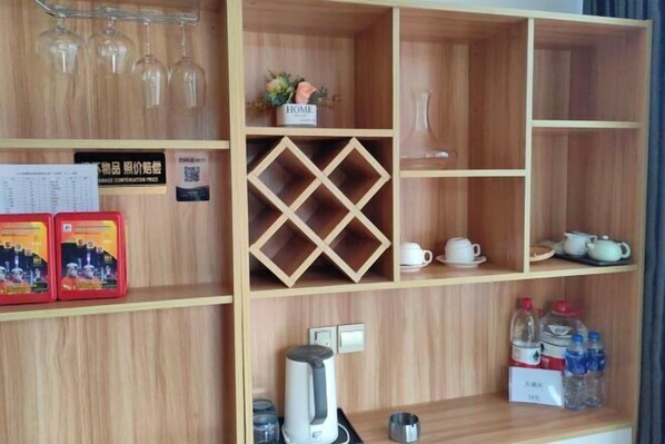 A hotel room with wooden shelves, a coffee maker, a kettle, and a water dispenser. - Yunshan Villa (Xiachuan Island) (Taishan)
