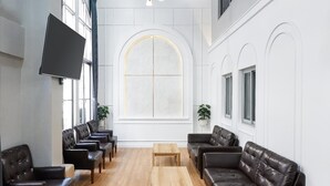 A spacious room with leather sofas, wooden tables, and large windows. - G5 Hostel Bangkok (Bangkok)