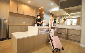A hotel reception area with a counter, a refrigerator, and wooden cabinets. - G5 Hostel Bangkok (Bangkok)