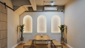 A conference room with a long table, three arched windows, and potted plants. - G5 Hostel Bangkok (Bangkok)