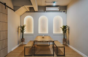 A conference room with a long table, three arched windows, and potted plants. - G5 Hostel Bangkok (Bangkok)