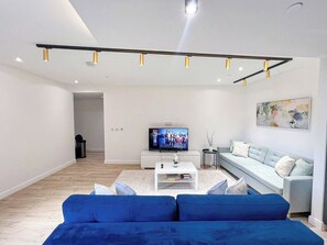 A modern living room with a flat-screen TV, a sofa, a coffee table, and a minimalist design.