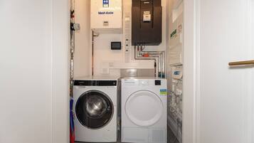 A laundry room with a Siemens washing machine, a white dryer, and a Vent-Axia water heater.