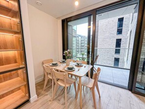 A dining area with a table set for four, chairs, and a view of a building through a glass door.