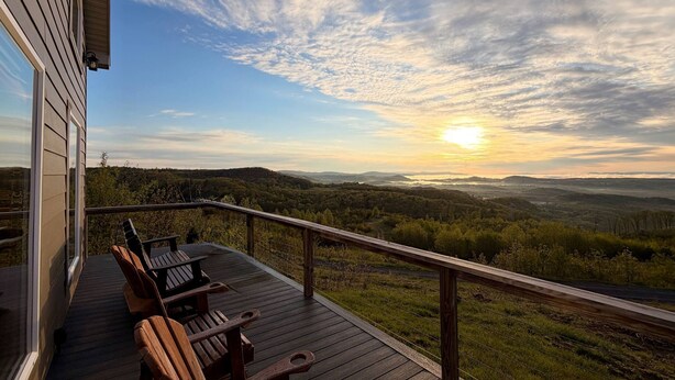 A deck with wooden chairs overlooking a scenic landscape with a sunset. - Million Dollar View Home by New River Gorge Park (Cool Ridge)