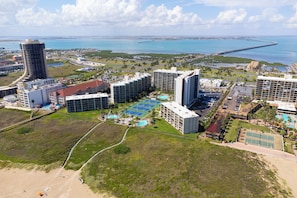 Um complexo hoteleiro costeiro com vários edifícios, uma praia e vista para o oceano.