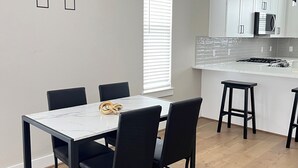 Moderni keittiö, jossa on valkoiset kaapit, sisäänrakennettu mikroaaltouuni ja kaasuliesi.