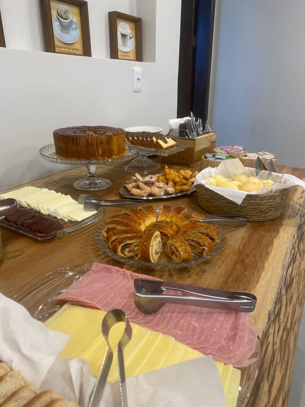 Una mesa de buffet con diversos alimentos, incluyendo un pastel, productos de pastelería y una variedad de embutidos.