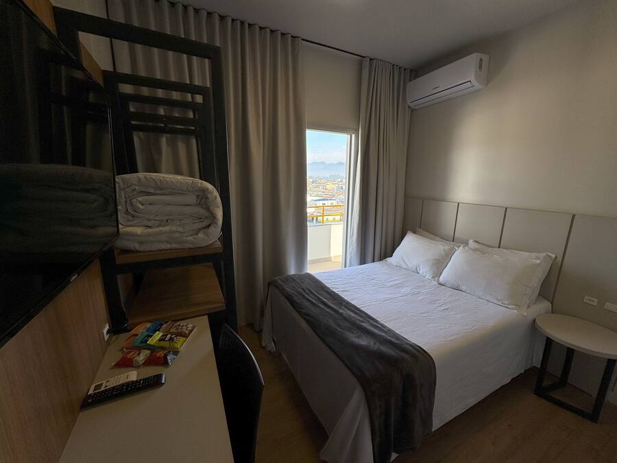Habitación de hotel con literas, una cama individual, una mesita con un control remoto y un equipo de aire acondicionado.