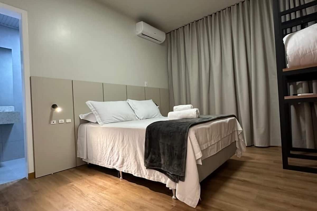 Ett modernt hotellrum med en säng, en garderob, en inbyggd bänk och en taklampa.