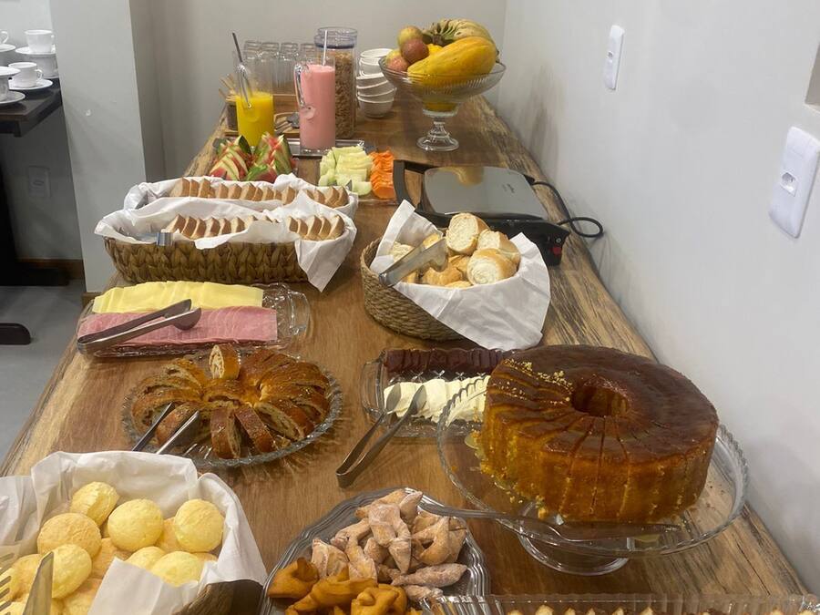 Una mesa de buffet con diversos alimentos, entre ellos pan, bollería y postres.