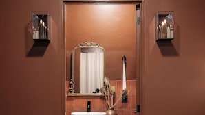 A bathroom with a large mirror, a sink, and two wall-mounted lights.