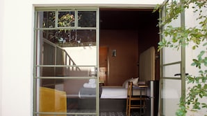 A hotel room with a bed, a chair, a radiator, and a small table.