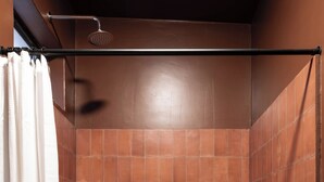 A bathroom with a shower, a towel rack, a candle holder, and a small stool.