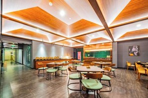 Un espace intérieur spacieux, aménagé avec différents coins salon, un comptoir et un écran fixé au mur.