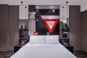Ein modernes Hotelzimmer mit einem großen Bett, einem Schreibtisch mit Computer und einer Wand, die mit Souvenirs einer Reise dekoriert ist.
