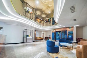 Un hall d’hôtel moderne doté d’un plafond incurvé, d’un espace salon, d’un comptoir d’accueil et offrant une vue sur le paysage urbain grâce à de grandes fenêtres.