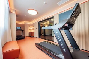 Une chambre d’hôtel équipée d’un tapis de course, d’une télévision et d’un coin salon.