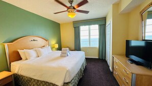 A hotel room with a bed, a television, a ceiling fan, and a view of the sea through the window. - 1Bed/1Bath Suite. Daytona Beach, FL! (Daytona Beach)
