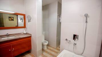 A bathroom with a sink, mirror, toilet, and shower.
