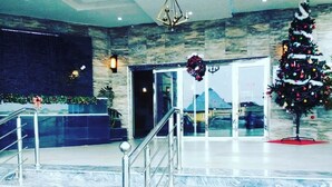 A lobby with marble flooring, a Christmas tree, and a reception desk. - VINMILAN Hotel & Resort (Asaba)