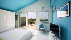A modern bedroom with a bed, a TV, and a chair. There is a sliding glass door leading to an outdoor area.