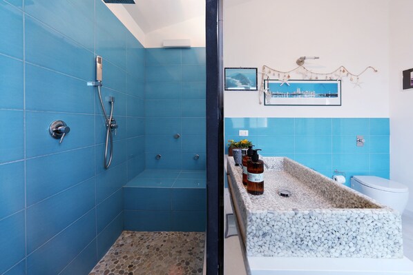 A bathroom with blue tiles, a white bathtub, and a toilet.