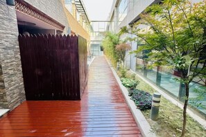 A narrow corridor with a wooden floor, a dark fence, and a glass wall on one side. - Yueting Hotel Selected (Nantong Gongnong North Road) (Nantong)