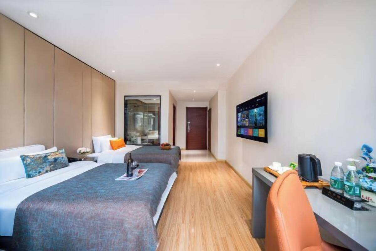 A hotel room with a bed, a desk with a chair, a TV, and a window.