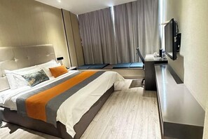 A modern hotel room with a large bed, a desk, and a television.