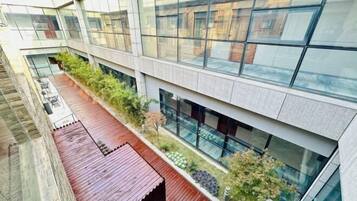 A modern building with a glass facade, a wooden deck, and a landscaped area with plants.