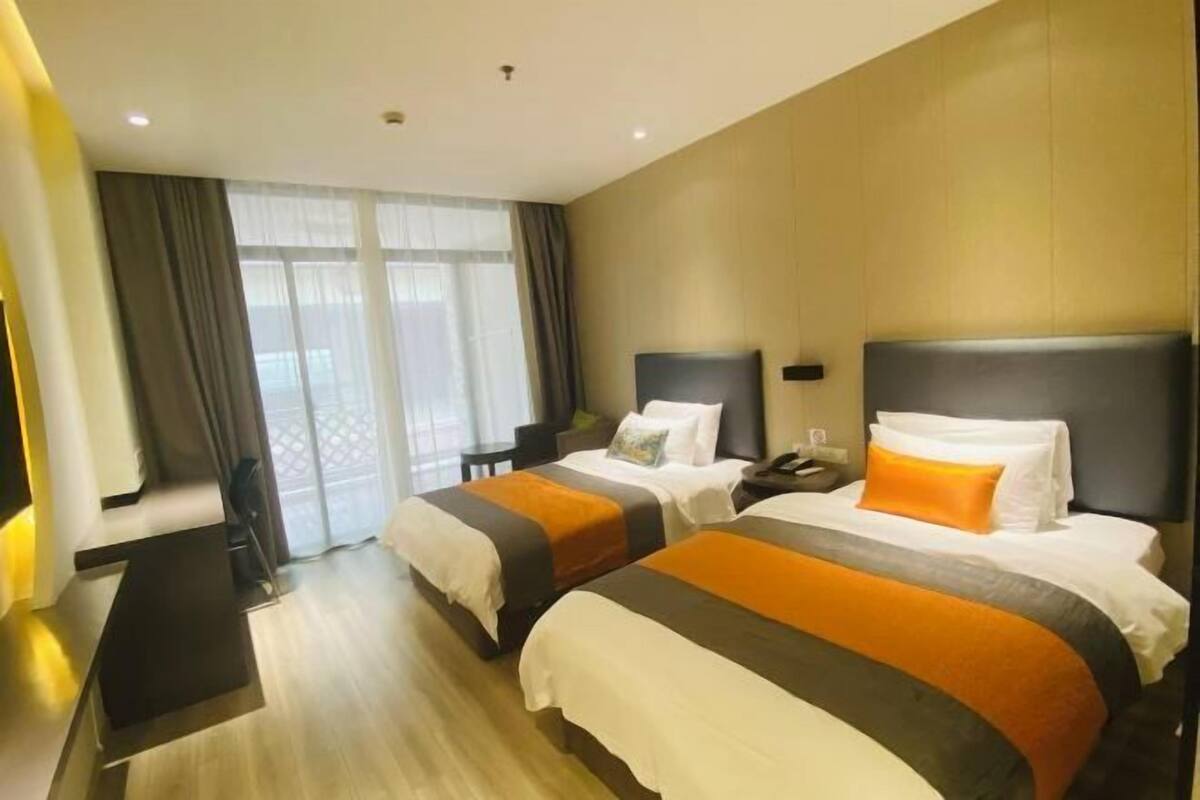 A hotel room with two beds, a desk, and a chair.