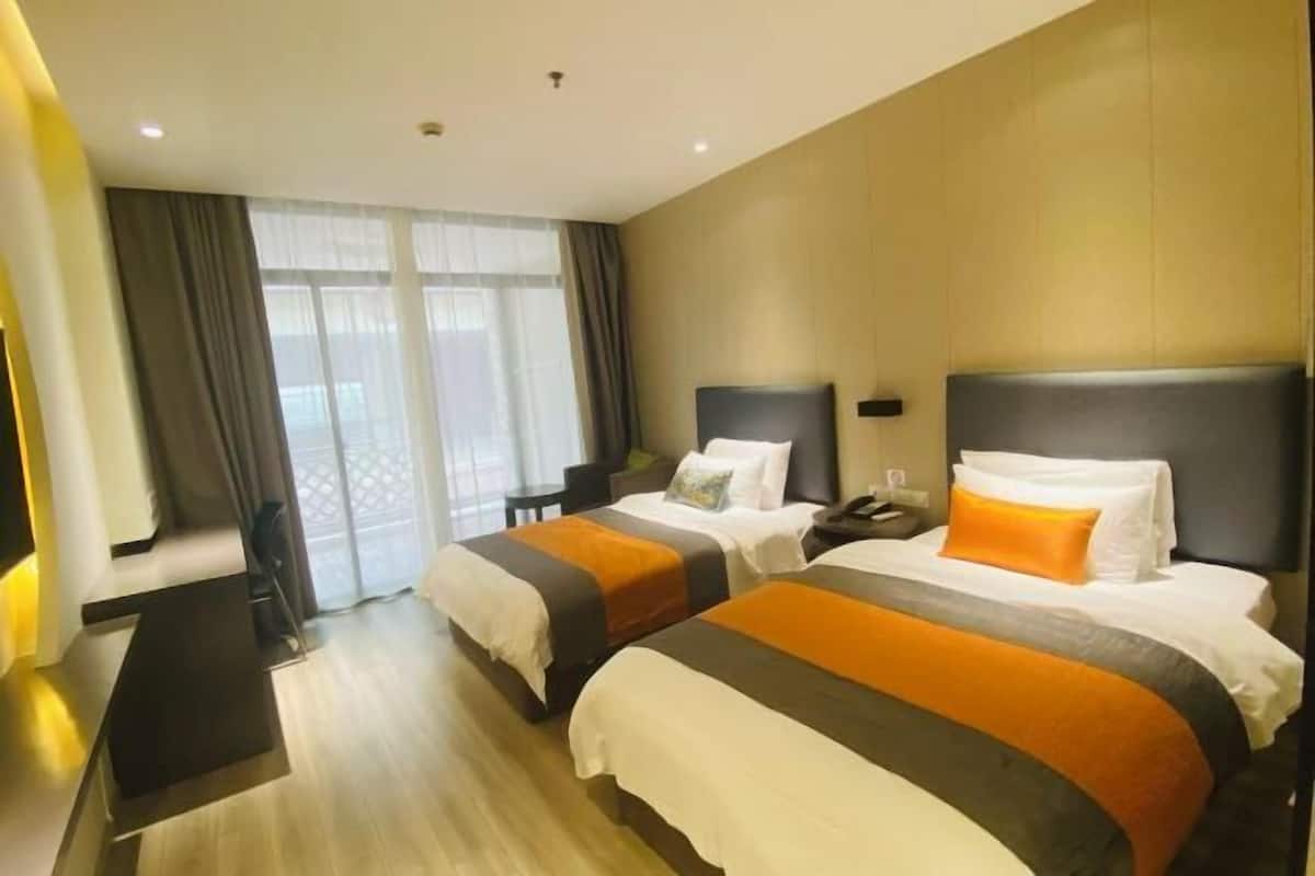 Ein Hotelzimmer mit zwei Betten, einem Schreibtisch und einem Stuhl.